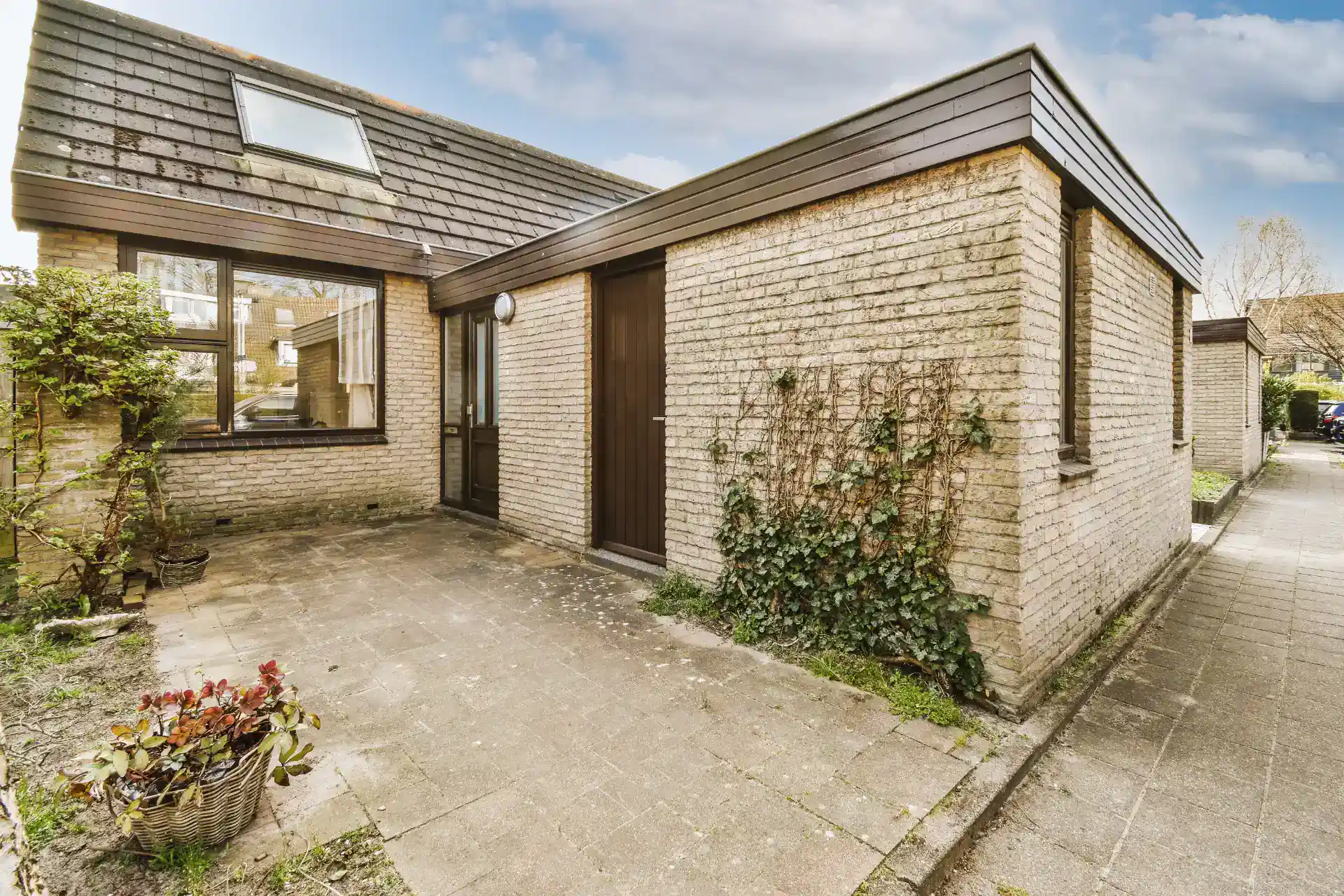 Beskåret træterrasse foran hus med 1-2 døre og vinduer, velegnet til tømrer- og snedkerarbejde.